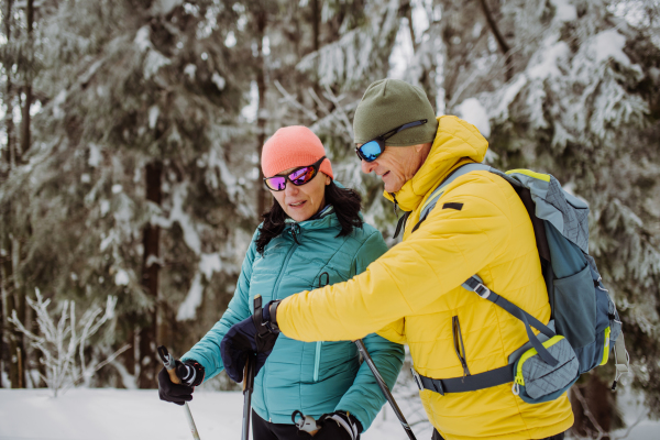 Senior couple checking a smartwatch during winter skiing.