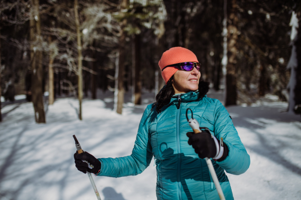 Senior woman skiing alone in the middle of snowy forest.