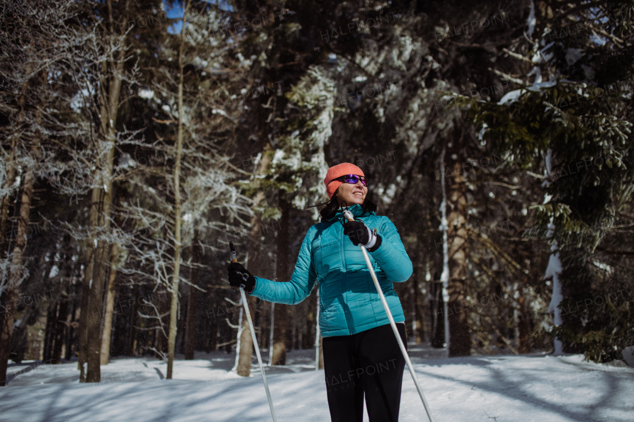 Senior woman skiing alone in the middle of snowy forest.