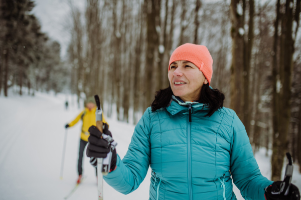 Senior couple skiing together in the middle of snowy forest