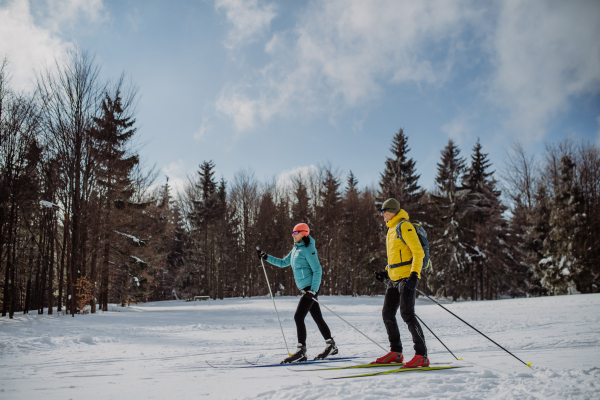 Senior couple skiing together in the middle of snowy forest.