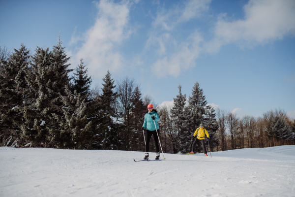 Senior couple skiing together in the middle of snowy forest.