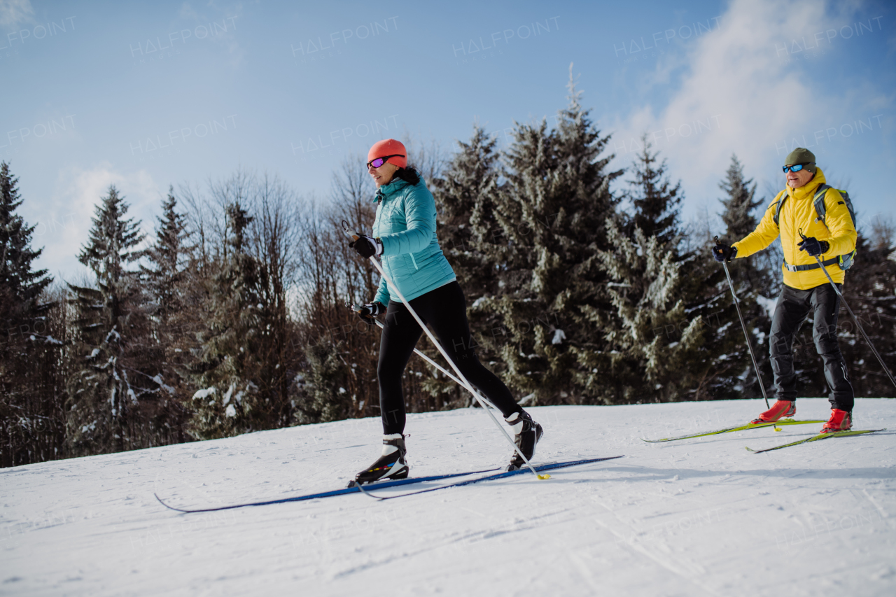 Senior couple skiing togetherin the middle of snowy forest