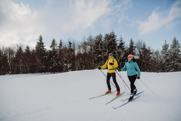 Senior couple skiing together in the middle of snowy forest.