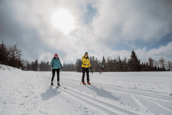 Senior couple skiing together in the middle of snowy forest.