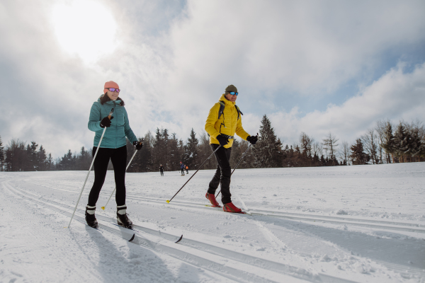 Senior couple skiing together in the middle of snowy forest