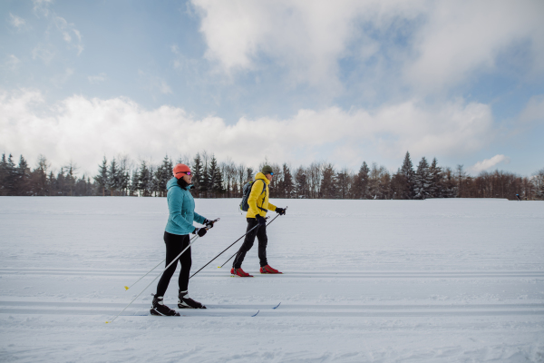 Senior couple skiing together in the middle of snowy forest