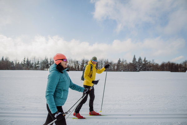 Senior couple skiing together in the middle of snowy forest