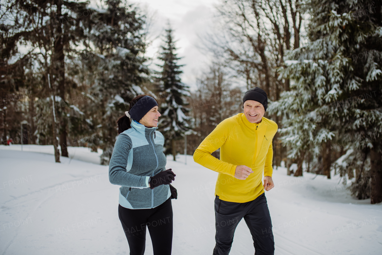 Senior couple jogging together in winter nature.