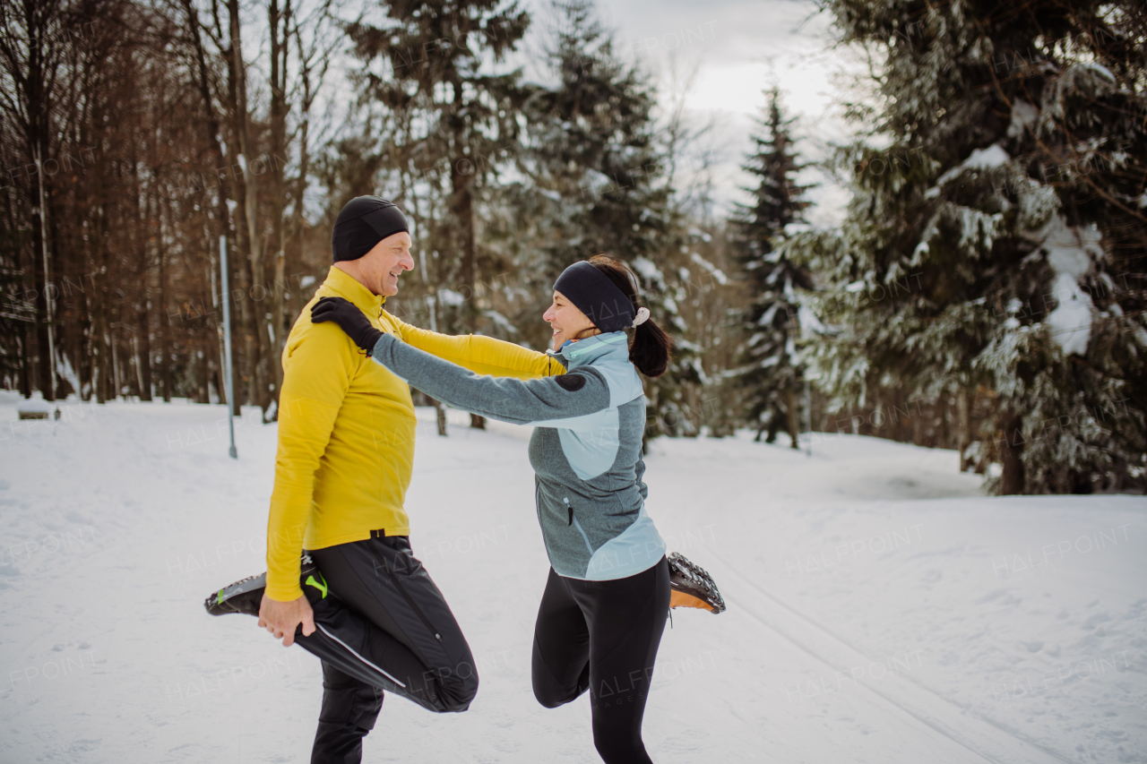 Senior couple warming-up in forest before winter hike.