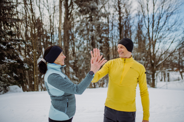 Senior couple having break after jogging in a winter forest.