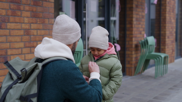 Father button up jacket to his little son during city walk.