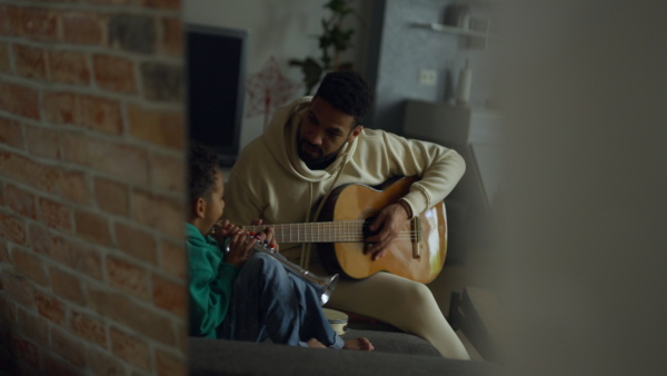 Father and son playing on musical instruments in their living room, having fun together.