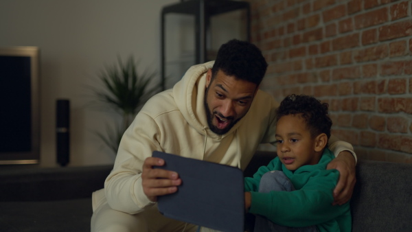 Young father with his looking something on digital tablet, enjoying time together.