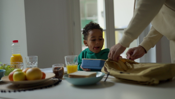 Young father and his little son having breakfast together in their flat.