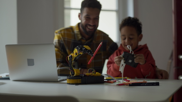 Father and his son constructing and playing with robotic toy.