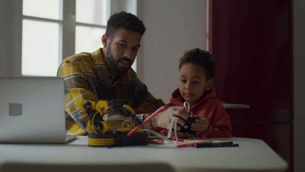 Father and his son constructing and playing with robotic toy.