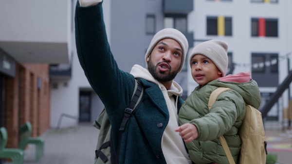 Young father and his little son during outdoor walk in a city, holding him.