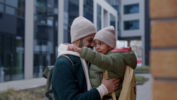 Young father and his little son during outdoor walk in a city, holding him.