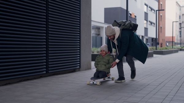 Father teaching his son skateboarding outdoor in a city.