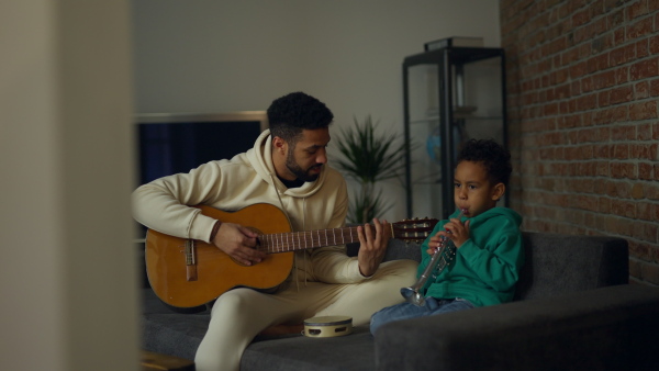 Father and son playing on musical instruments in their living room, having fun together.