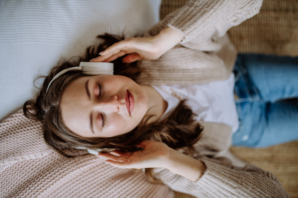 Top view of young woman listening music trough a headphones.