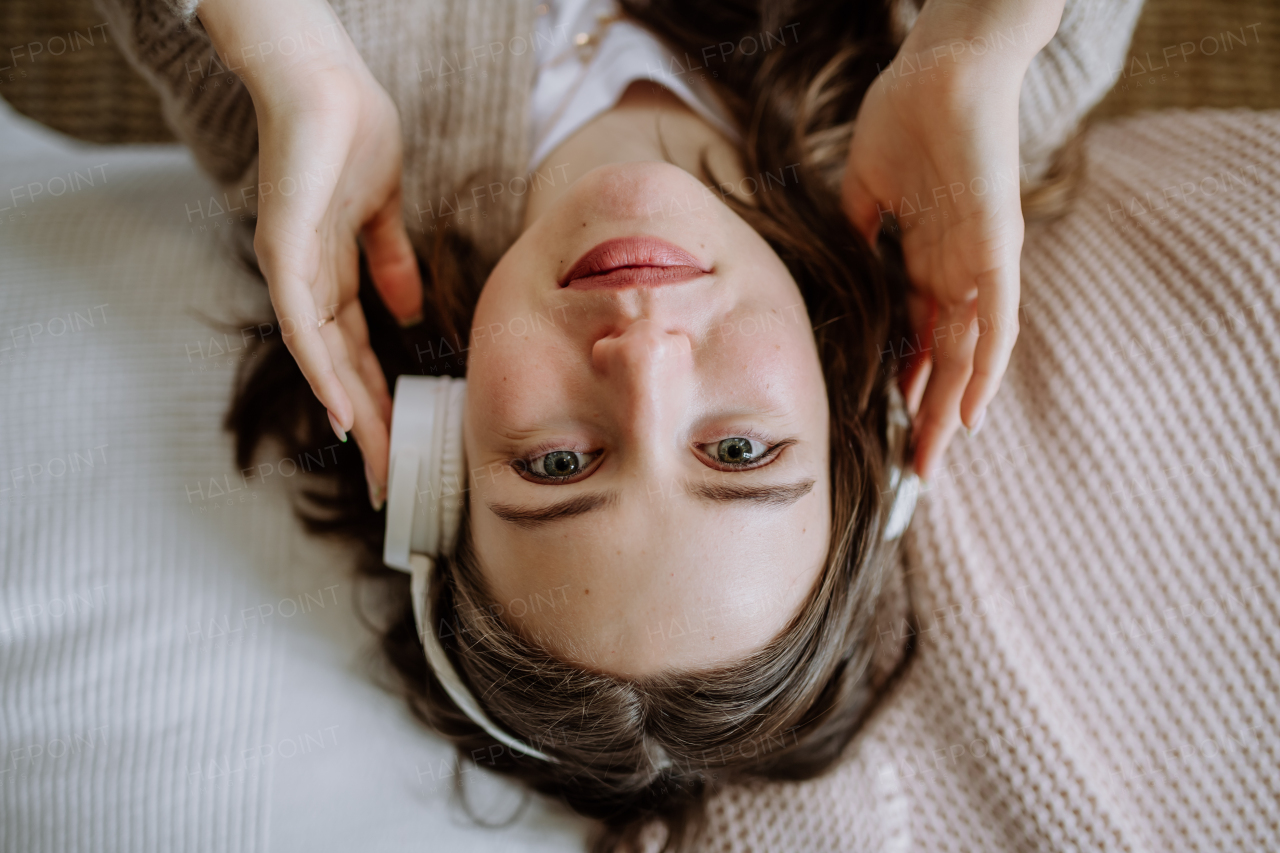 Top view of young woman listening music trough a headphones.