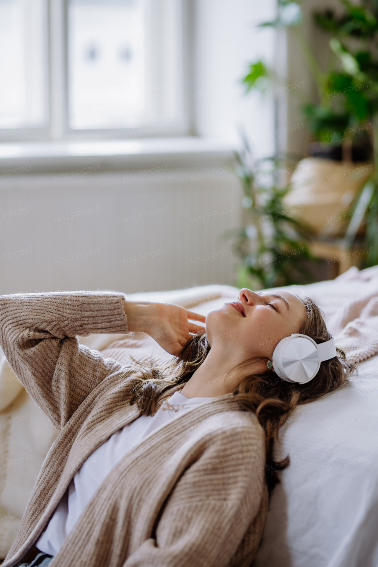 Young woman listening music trough headphones in the apartment.