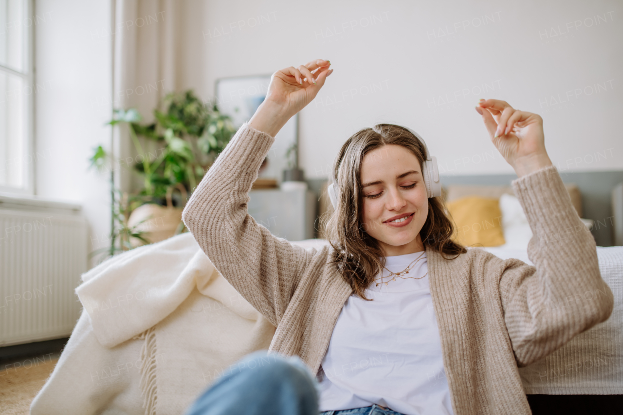 Young woman listening music trough headphones in the apartment.