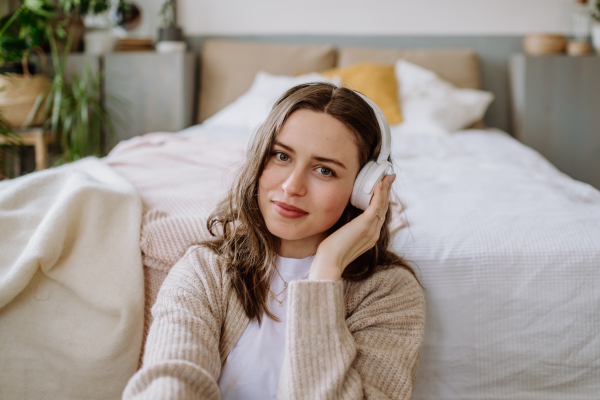 Young woman listening music trough headphones in the apartment.