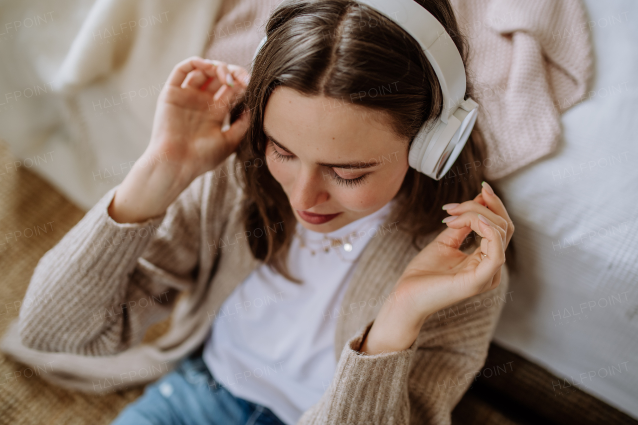 Young woman listening music trough headphones in the apartment.