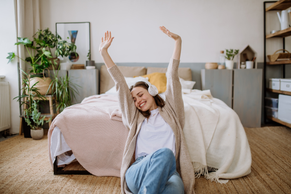 Young woman listening music trough headphones in the apartment.