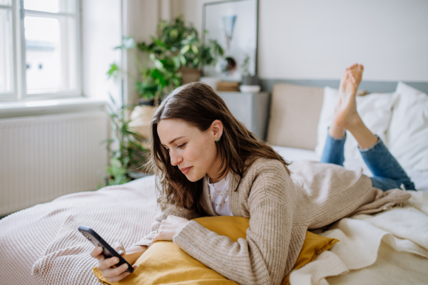 Young woman scrolling her smartphone in an apartment.