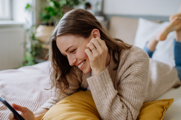 Young woman scrolling her smartphone in an apartment.