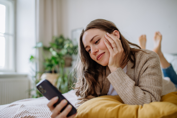 Young woman scrolling her smartphone in an apartment.