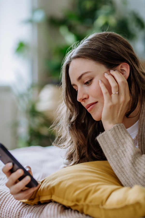 Young woman scrolling her smartphone in an apartment.