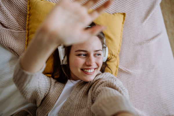 Top view of young woman listening music trough a headphones.