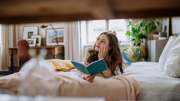 Young woman enjoying leisure time in her apartment, reading a book.