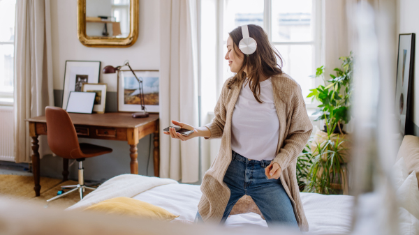 Young woman listening music trough headphones in the apartment.