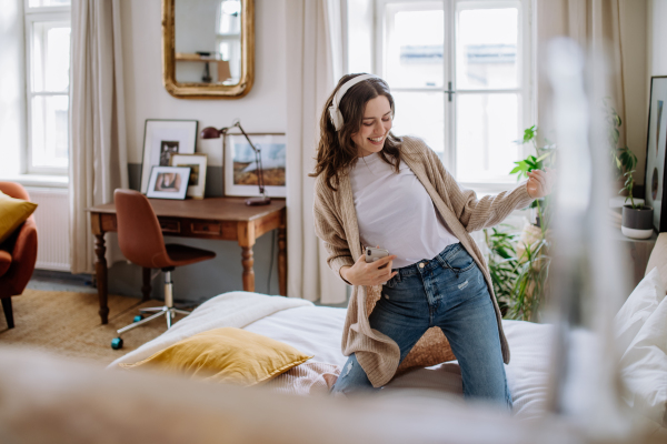 Young woman listening music trough headphones in the apartment.