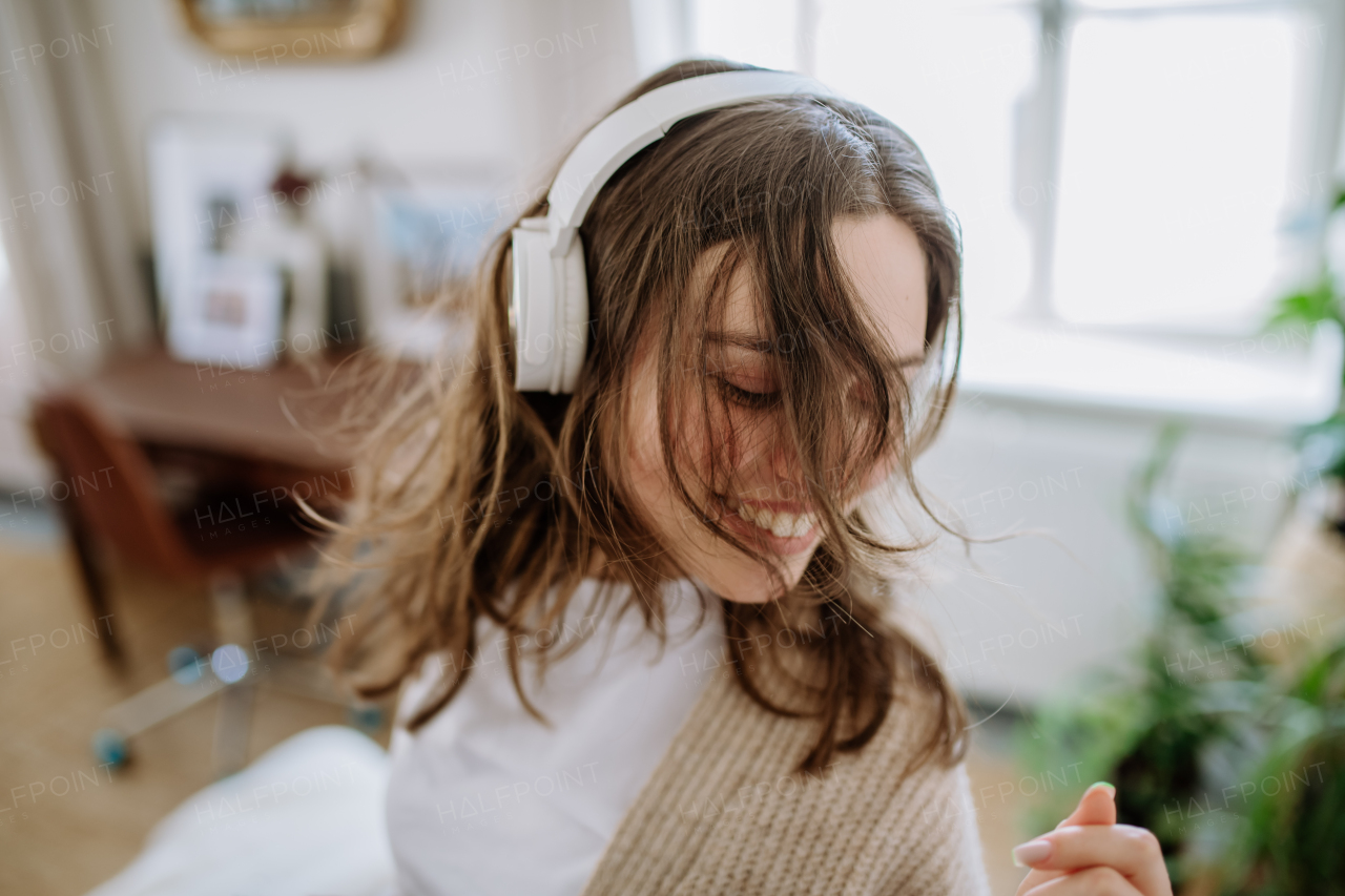 Young woman listening music trough headphones in the apartment.