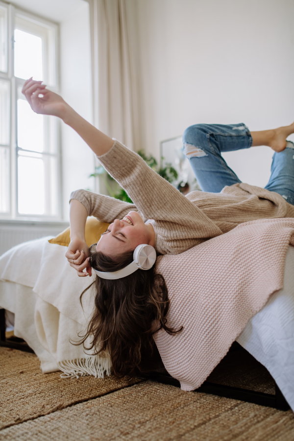 Young woman listening music trough headphones in the apartment.