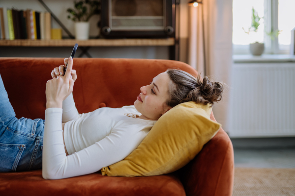 Young woman scrolling her smartphone in an apartment.