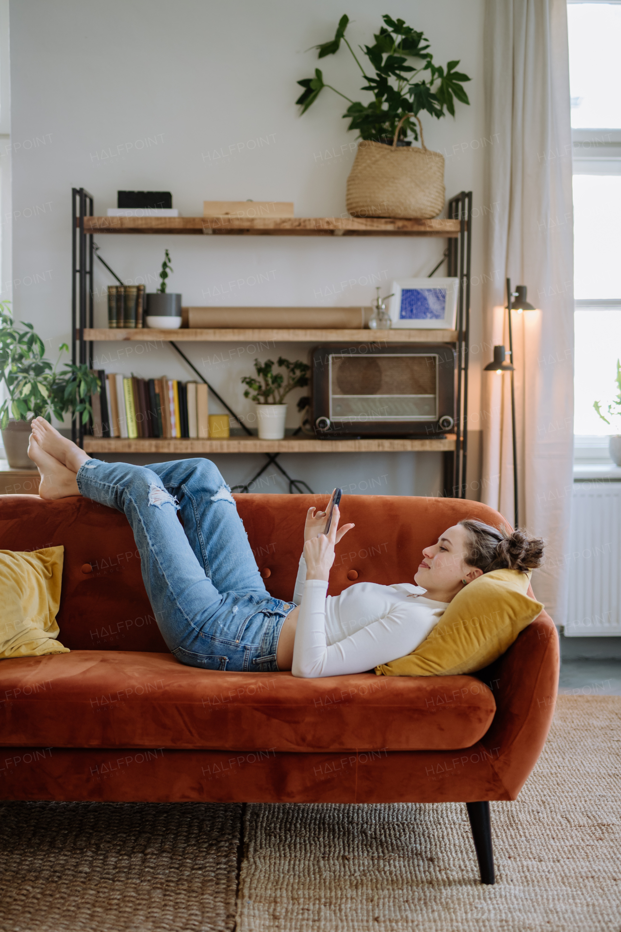 Young woman scrolling her smartphone in an apartment.