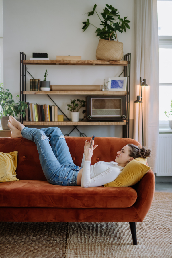 Young woman scrolling her smartphone in an apartment.