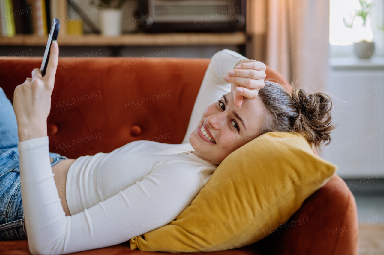 Young woman scrolling her smartphone in an apartment.