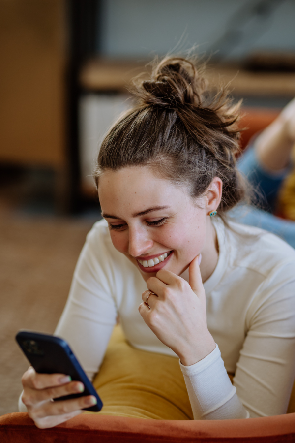 Young woman scrolling her smartphone in an apartment.