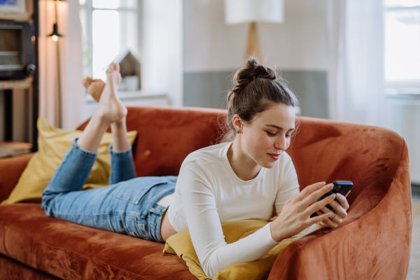 Young woman scrolling her smartphone in an apartment.