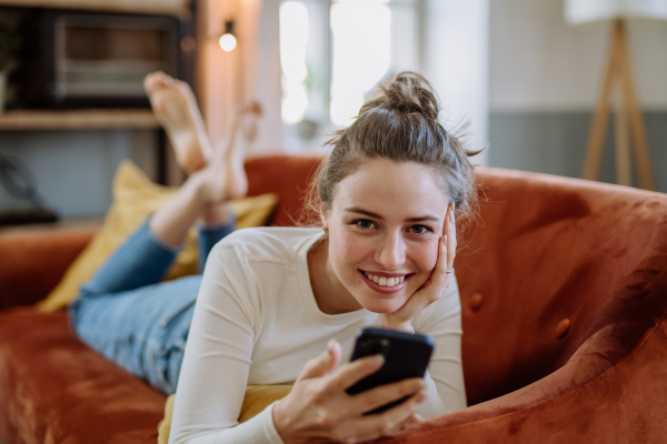 Young woman scrolling her smartphone in an apartment.