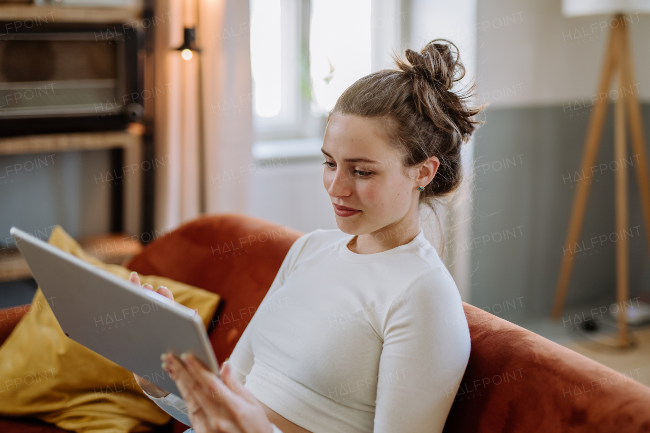 Young woman with digital tablet resting in the apartment.